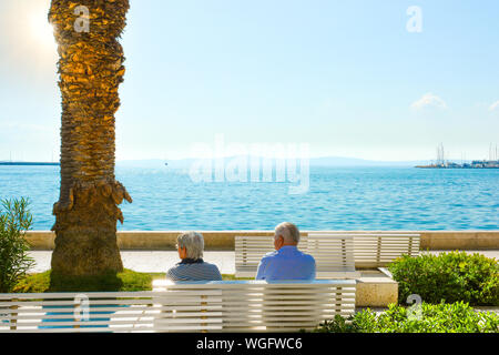 Ein reifes Paar sitzen auf einer Bank und Blick auf die Adria an der Uferpromenade Riva genießen an der Dalmatinischen Küste von Split Kroatien Stockfoto