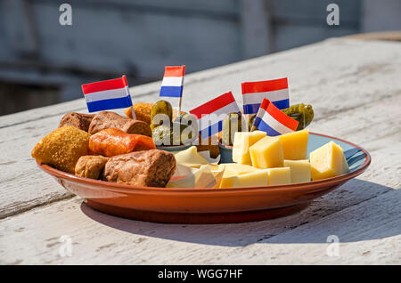 Eine bittergarnituur, traditionelle niederländische Platte von Snacks vor dem Abendessen, einschließlich Käse, Frikadellen, Pickles, mit Flaggen dekoriert, auf einem Holztisch in einem Stockfoto