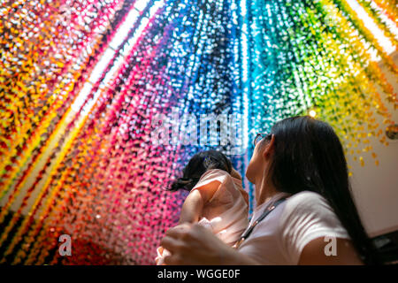 Jungen asiatischen Mutter ihr Mädchen mit Blick auf die Rainbow Paper cranes Holding. Stockfoto