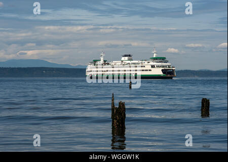 Edmonds Ferry verlässt das Terminal in den Puget Sound mit Holzpfeilern im Vordergrund Stockfoto