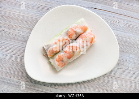 Blick von oben auf nem Cuon (frisch Vietnamesisch nem Rolle mit Garnelen, Mango und Ingwer) auf die weiße Platte auf hölzernen Tisch Stockfoto
