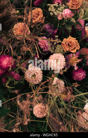 Bukett von getrockneten Blumen auf einem hölzernen Hintergrund. Schöne verdorrte trockene Blumen. Rosen, Weizen und trockenes Gras. Stockfoto