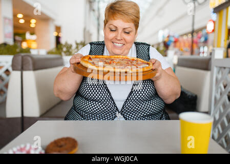 Fette Frau essen Pizza, ungesunde Nahrung Stockfoto