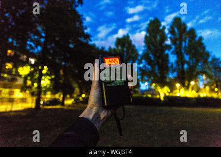 Hand mit einem bat-Detektor auf eine Fledermaus Spaziergang im Park, London, UK Stockfoto