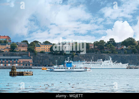 Stockholm, Schweden - 2 August 2019: Ausblick auf die Küste der Insel Södermalm mit Fähre Nummer 82 und Birger Jarl im Sommer Tag Schiff Stockfoto