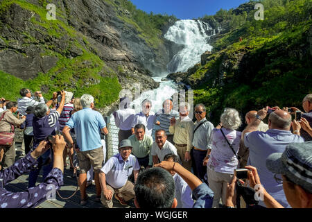 Kjosfossen-Waterfall, machen Sie Fotos von Touristen, Wasserfall in der Nähe von Fureberget, Berg, Felsen, Wiese, Bäume, Himmel, Flåm, Sogn und Fjordane, Norwegen, Stockfoto