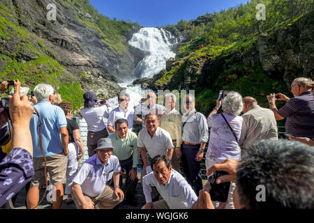 Kjosfossen-Waterfall, machen Sie Fotos von Touristen, Wasserfall in der Nähe von Fureberget, Berg, Felsen, Wiese, Bäume, Himmel, Flåm, Sogn und Fjordane, Norwegen, Stockfoto