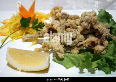 Die gebratenen Frosch Gericht mit Zitrone und Gemüse auf dem weißen Teller Stockfoto