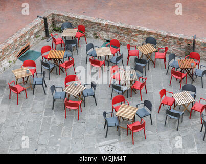 Leere cafe Holztische und rote und schwarze Stühle, Ansicht von oben. Alte Festung Livorno, Italien. Stockfoto