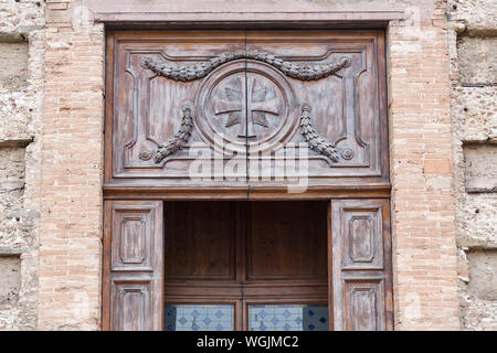 Alte Holztür mit geschnitzten Kreuz closeup in Livorno, Italien. Stockfoto