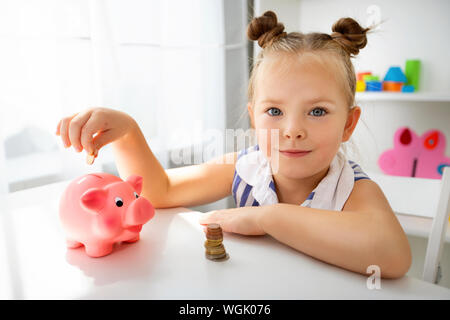 Süße kleine Mädchen Träume mit einem Sparschwein. Planung, um Geld zu sparen. Stockfoto