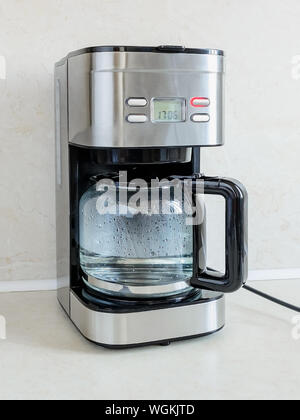 Der erste Einsatz der Tropf-stopp-Art Kaffeemaschine mit sauberem Wasser ohne Kaffee sein sollte. Rote Taste zeigt den Prozess vor sich geht. Warmes Wasser ist im Glas Krug Stockfoto