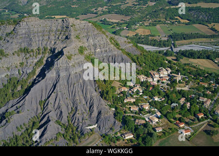 LUFTAUFNAHME. Kleines Dorf zwischen Badlands und Ackerland. Marcoux, Bléone Valley, Alpes de Haute-Provence, Frankreich. Stockfoto