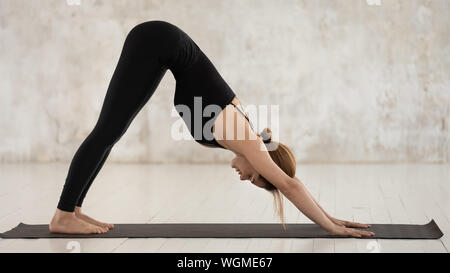 Junge Frau mit Yoga in den nach unten schauenden Hund, Adho Mukha Svanasana Stockfoto