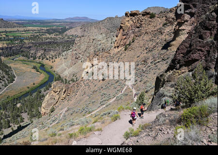 Wanderer auf Elend Ridge Trail in Smith Rock State Park in der Nähe von Terrebonne, Oregon an einem wolkenlosen Sommertag. Stockfoto