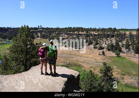 Junges Paar beim Blick vom Elend Ridge Trail in Smith Rock State Park, Oregon auf klaren, wolkenlosen Sommertag. Stockfoto