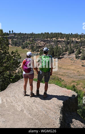 Junges Paar beim Blick vom Elend Ridge Trail in Smith Rock State Park, Oregon auf klaren, wolkenlosen Sommertag. Stockfoto