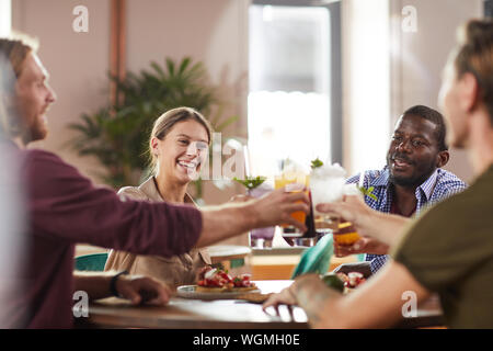 Multi-ethnischen Gruppe von Freunden anstoßen beim Sitzen am Tisch im Cafe genießen Sie erfrischende Getränke kalt, kopieren Raum Stockfoto