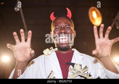 Low Angle Portrait von Afro-amerikanische Mann im Halloween Kostüm posiert als Teufel mit Hörnern während der Party, Kopie Raum Stockfoto