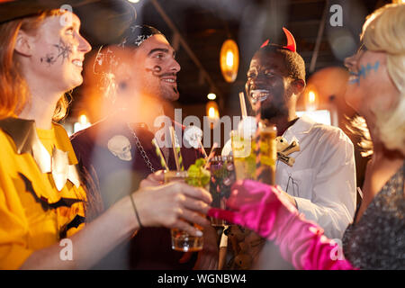 Multi-ethnischen Gruppe von Freunden tragen Halloween Kostüme trinken Cocktails Party im Club und Spaß haben Stockfoto