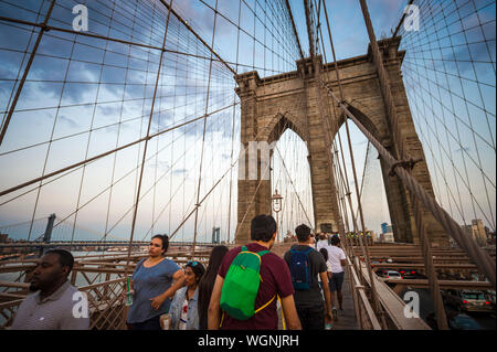 NEW YORK - 26. AUGUST 2017: Touristen und Einheimische Kampf um Platz auf der überfüllten Fußgängerzone über die Brooklyn Bridge bei Sonnenuntergang. Stockfoto