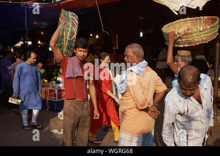 Träger mit ihren Körben bei Crawford Market (Mahatma Jyotiba Phule Market) in Mumbai, Indien, ein Kollege (r) spuckt Rot betel Saft Stockfoto