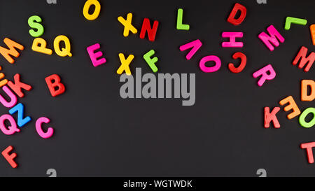 Bunte plastik Buchstaben des englischen Alphabets auf einem schwarzen Kreidetafel, Kopieren, Zurück zur Schule Stockfoto