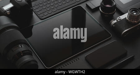 Dunkle trendigen Arbeitsplatz mit Smartphone, Tablet, Kamera und Bürobedarf auf schwarzem Leder Schreibtisch Stockfoto