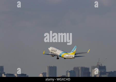 Eine Boeing 737-781 der Billigfluggesellschaft Air Do startet vom Flughafen Haneda vor den Gebäuden in Tokio, Japan. Stockfoto