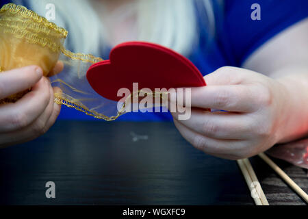 Frau wickeln ein roter Schaum Herzen in Gold Stoff Stockfoto