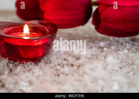 Tulpe Blume und herzförmige Kerze auf einem Schnee wie Hintergrund. Valentinstag Konzept. Stockfoto