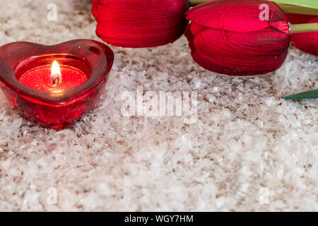 Tulpe Blume und herzförmige Kerze auf einem Schnee wie Hintergrund. Valentinstag Konzept. Stockfoto