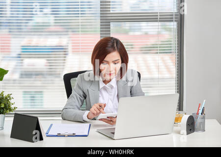 Asiatische Geschäftsfrau oder Buchhalter Arbeiten zeigen graph Diskussion und Analyse Daten Diagramme und Grafiken und mit einem Taschenrechner Zahlen zu berechnen. B Stockfoto