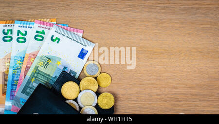 Europäische Banknoten und Münzen in schwarzem Leder Brieftasche auf Holz- Hintergrund. Euro Geld. Stockfoto