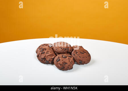 Vier köstliche, braune Lebkuchen liegen auf einem weißen Tisch, hinter einem gelben Hintergrund Stockfoto