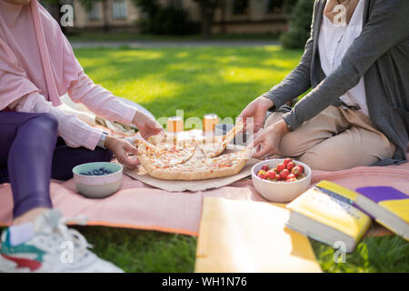 Zwei Studenten teilen cheesy, Pizza, während außerhalb Essen Stockfoto