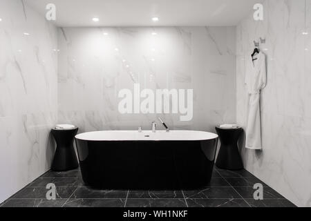 Freistehende Badewanne, stilvoll minimalistisch Schwarz Schwarz und Weiß im Loftstil Bad. Badewanne, Waschtisch, Wände mit Marmor Fliesen Stockfoto