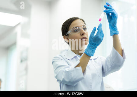 Portrait von aufmerksamen Frau, im Reagenzglas suchen Stockfoto