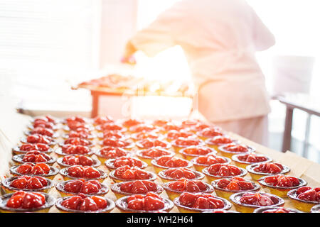 Ein konditor macht Kuchen mit frischen Erdbeeren in einem Törtchen. Sommer frische Nachtisch. Platz kopieren Stockfoto