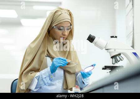 Fröhlicher junger medizinischer Arbeiter Prüfung der chemischen Reagenzien Stockfoto