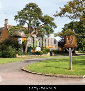 Village Green mit verzierten Eichenholz geschnitzte Ortsschild Lyddington, Rutland, England, Großbritannien Stockfoto