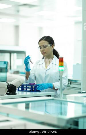 Junge Arbeitnehmer in Reagenzglas suchen konzentriert Stockfoto