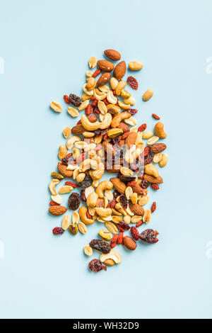 Mix aus verschiedenen Nüssen und Rosinen auf blauem Hintergrund. Ansicht von oben. Stockfoto