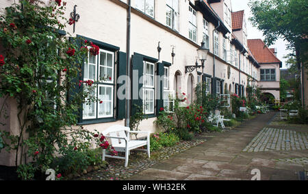 Schönen gemütlichen Innenhof mit Bänken, Pflanzen und Blumen in der Straße der alten Stadt, Lübeck, Deutschland Stockfoto