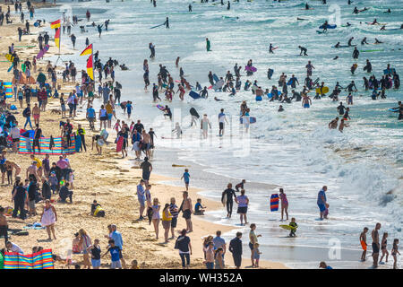 Urlauber genießen, sich an einer geschäftigen und überfüllten Fistral Beach in Newquay in Cornwall. Stockfoto