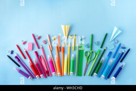 Vielzahl von Schulmaterial in Regenbogenfarben-Sequenz auf Pastell-blaue Hintergrund. Flach Stil. Zurück zum Konzept der Schule. Stockfoto