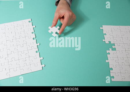 Hand das letzte Stück des Puzzles zur Vollendung der Aufgabe Stockfoto