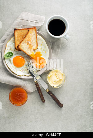 Frühstück serviert mit gebratenen Eiern, Brot, Marmelade, Butter und Kaffee auf den Tisch. Heathy Frühstück essen Stockfoto