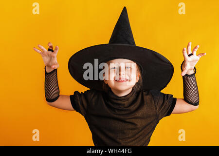 Halloween Party. Kleines Mädchen in eine Hexe Kostüm auf gelbem Hintergrund gekleidet. Stockfoto