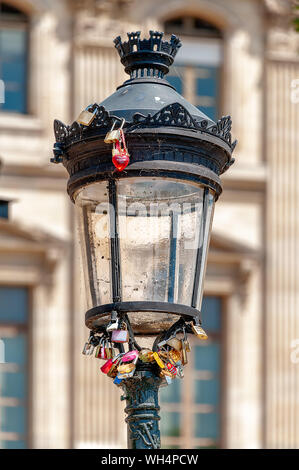 Bündel von Vorhängeschlössern und ein rotes Herz Schlüsselanhänger gesperrt auf eine strassenlaterne an der "Fußgänger-Brücke Pont des Arts" in Paris. Stockfoto